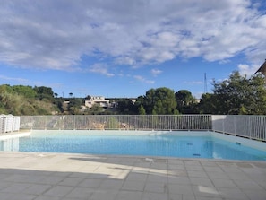 A swimming pool with a white fence, surrounded by a tiled deck, under a partly cloudy sky. - An ideal getaway for couples or families, just 10 minutes from Cassis. (Carnoux-en-Provence)