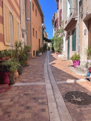 A narrow street with buildings on both sides, potted plants, and a clear blue sky. - An ideal getaway for couples or families, just 10 minutes from Cassis. (Carnoux-en-Provence)
