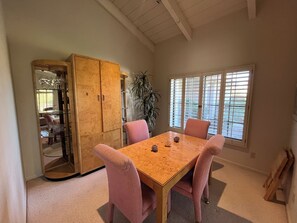 A dining area with a wooden table, pink upholstered chairs, a wooden cabinet, and a potted plant. - Quiet Scottsdale location for Snowbirds - near golf, restaurants and more. (Scottsdale)