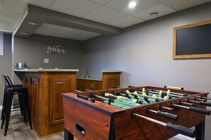 Ein Zimmer mit Tischfußballtisch, Barbereich und einer Wand mit der Aufschrift 'gather'.