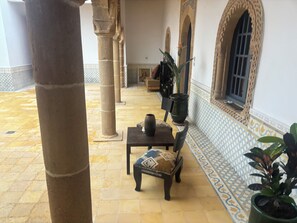A courtyard with columns, a bench, a table, and potted plants. - Luxury Moroccan Riad with Private Pool & Rooftop Terrace (Essaouira)