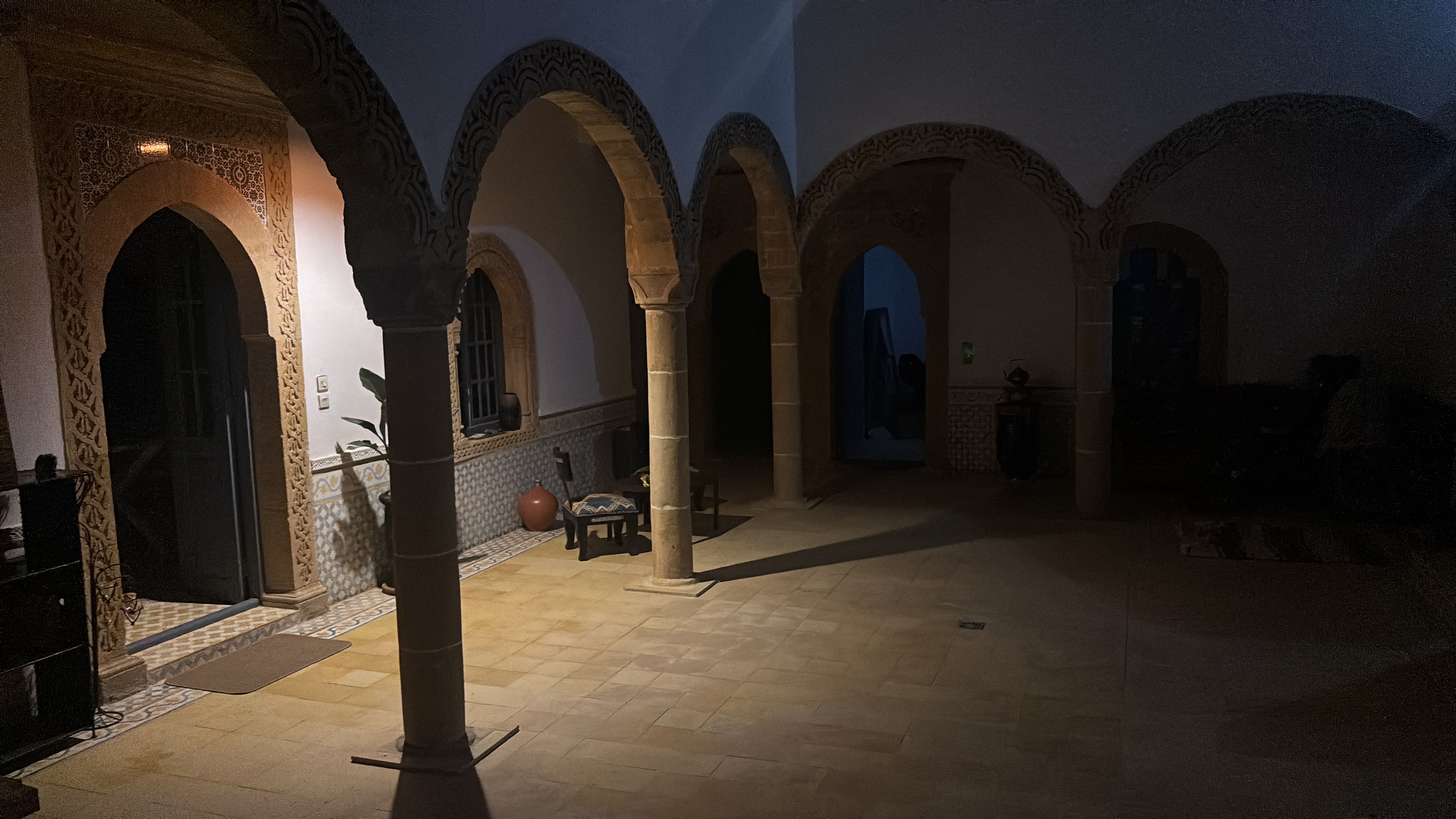 Ein Innenhof mit Bögen, Fliesenboden und einer Säule.