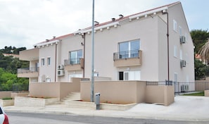 A multi-story residential building with balconies, air conditioning units, and a clear sky. - Cozy 1-bedroom apartment in Dubrovnik with AC, and private parking place (Dubrovnik)