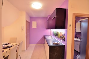 A narrow hallway with a dining area on one side, a kitchen with a sink and cabinets, and a door leading to another room. - Cozy 1-bedroom apartment in Dubrovnik with AC, and private parking place (Dubrovnik)