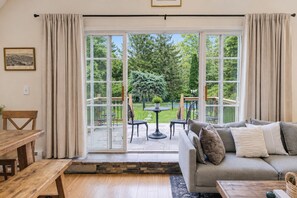 A room with a large sliding glass door leading to a patio with outdoor furniture and a view of greenery. - Penney Pines: A Cozy Catskills A-Frame (Catskill)