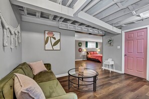 A modern living room with a green sofa, a glass coffee table, and a pink door. - Pink Paradise in Silver Spring Suburbs (Silver Spring)