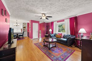 A living room with a black leather sofa, a coffee table, and a colorful rug. - Pink Paradise in Silver Spring Suburbs (Silver Spring)