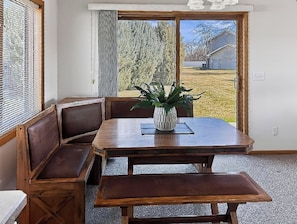 A dining area with a wooden table, benches, and a potted plant. - Peaceful & Private 2 Bed West End Home on a Gated Acre (Billings)