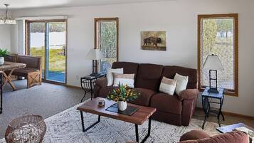 A living room with a sofa, coffee table, and a dining area with a table and chairs.
