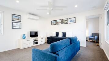 Ein modernes Schlafzimmer mit einem großen Bett, einem Fernseher, einem Deckenventilator und gerahmten Bildern an der Wand.