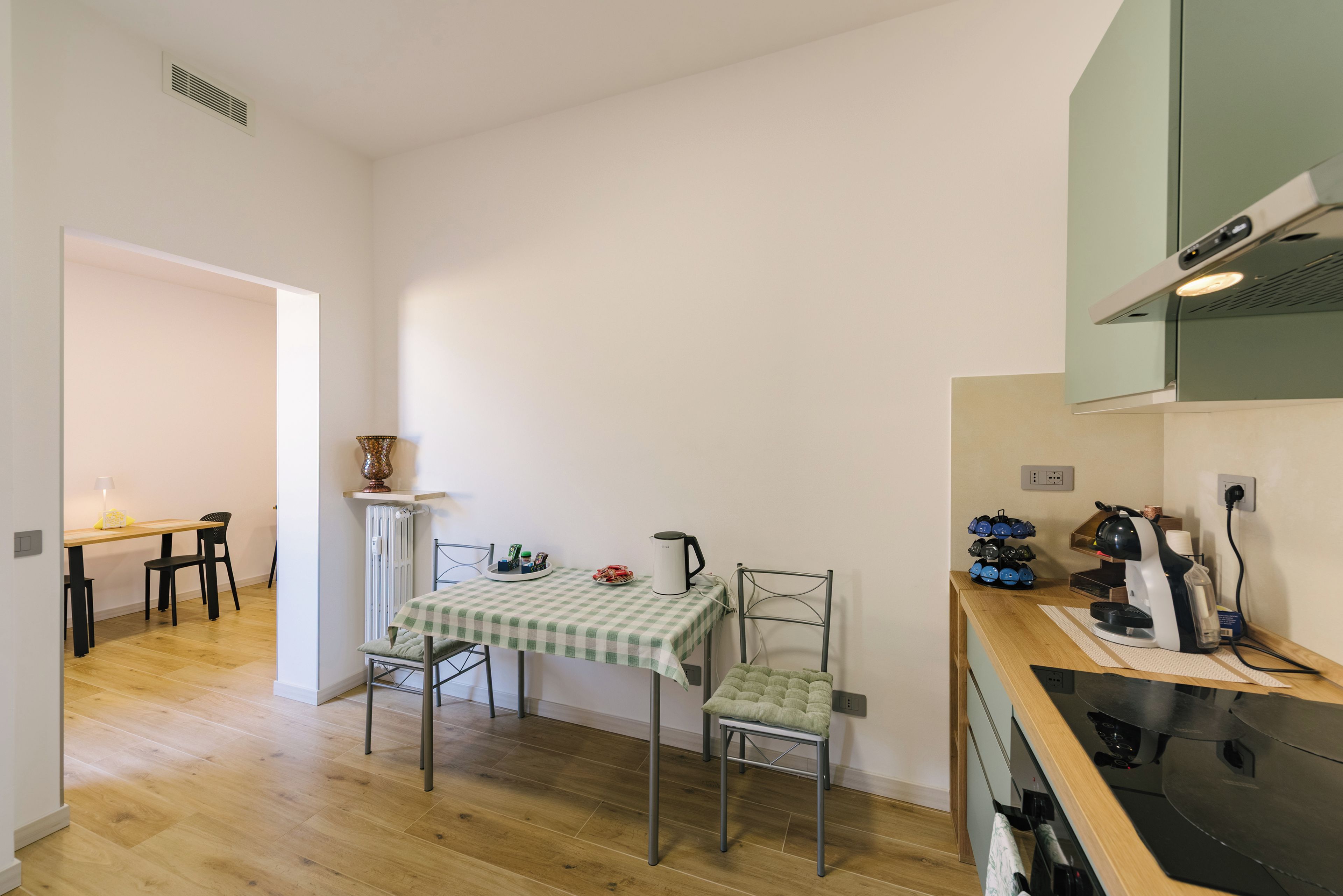 Una cucina piccola ma luminosa con un tavolo da pranzo, sedie e una macchina per il caffè.