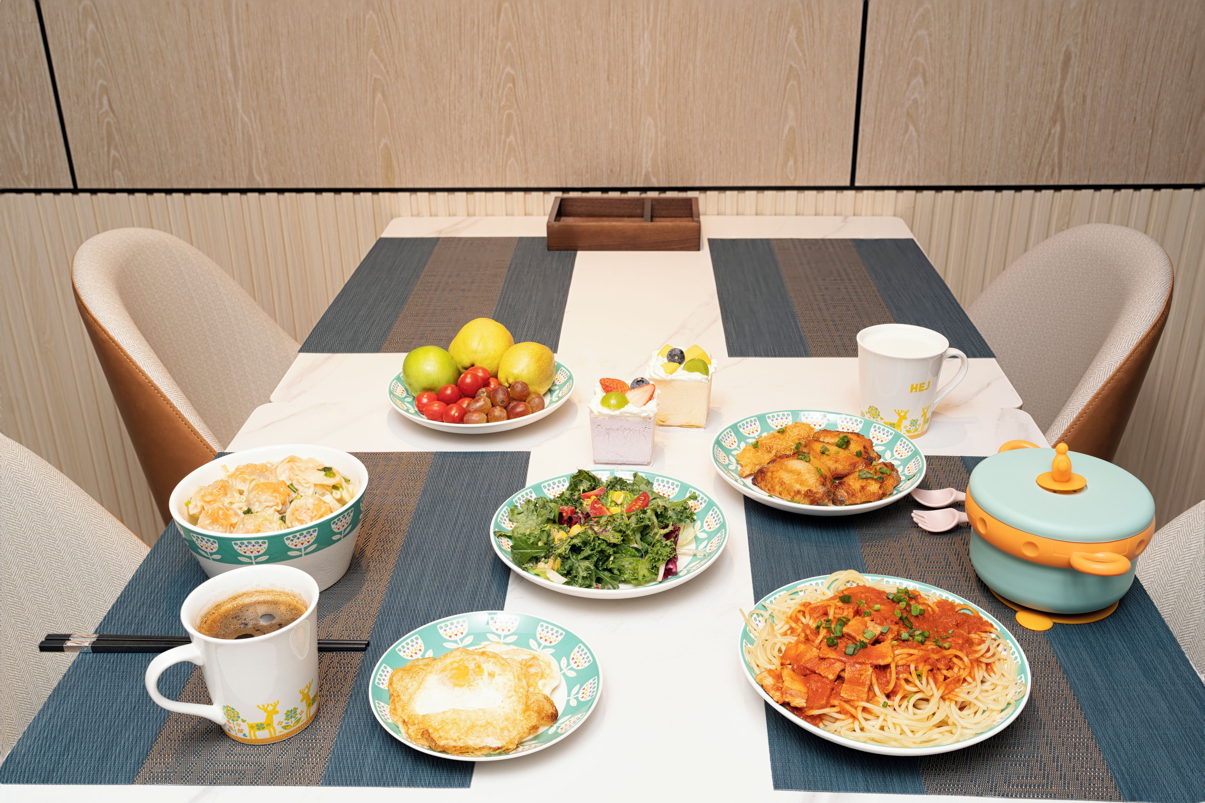A dining table set with various dishes, including pasta, salad, and fruit.