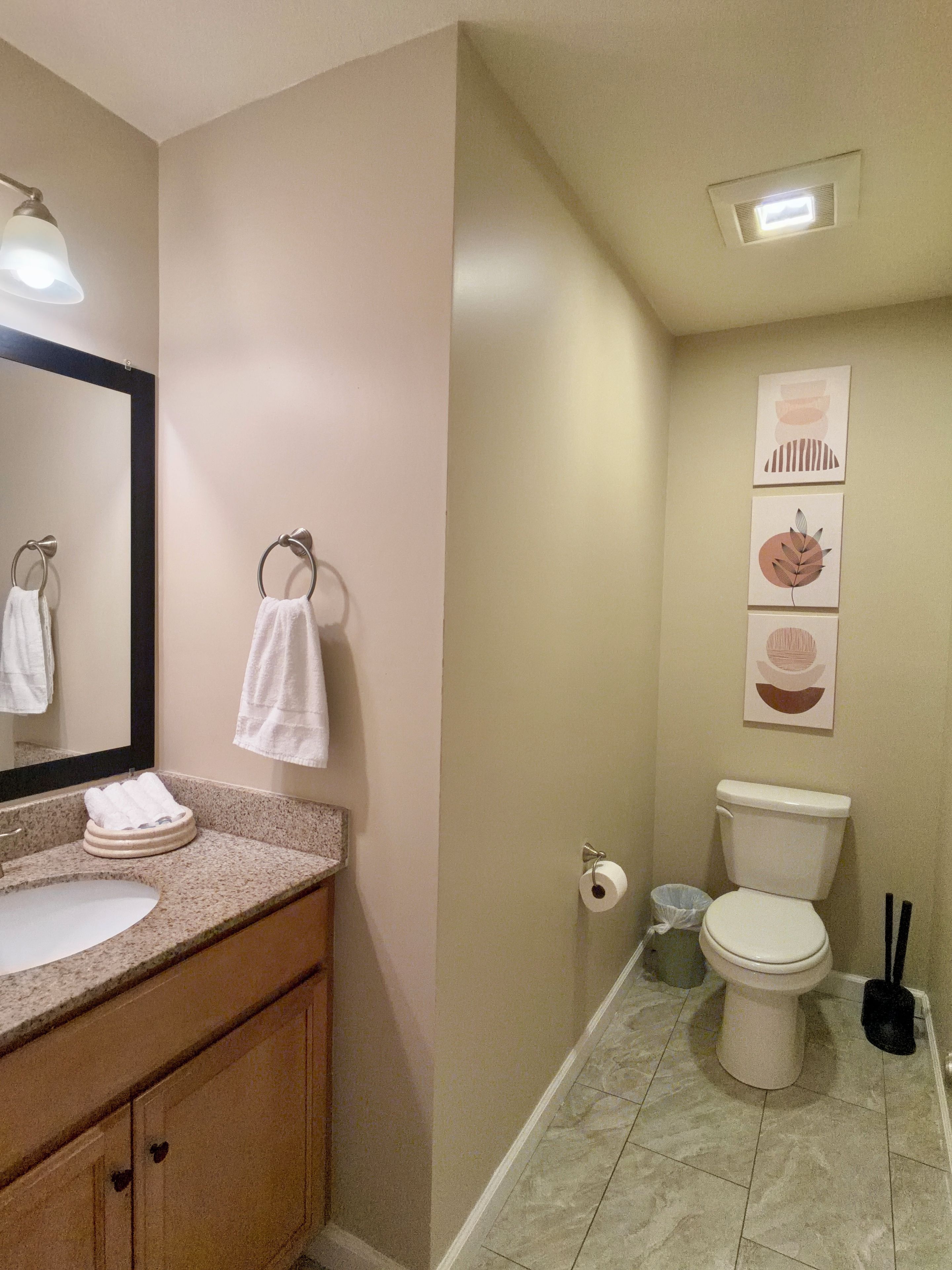 A bathroom with a sink, mirror, towel rack, toilet, and a ceiling light.