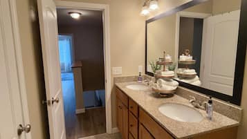 A bathroom with two sinks, a large mirror, and a towel rack.
