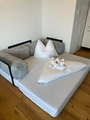 Une chambre moderne avec un canapé d’angle, un grand lit agrémenté d’un coussin décoratif et une armoire.