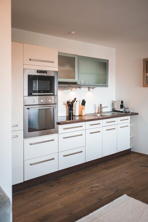 Une cuisine moderne dotée d’appareils électroménagers intégrés, de meubles blancs et d’un plan de travail en bois.