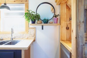 A kitchen with a wooden countertop, a sink, a hanging pendant light, a mirror, and potted plants. - Redshore River Cottage -Private Waterfront Retreat with Hot Tub (Lot 35)