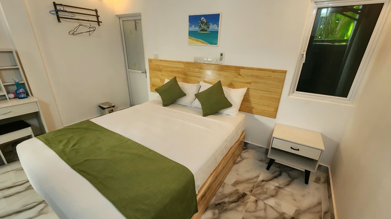 Une chambre d’hôtel avec un lit, une table de chevet, un bureau et une fenêtre.