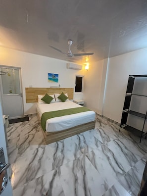 A hotel room with a bed, a ceiling fan, an air conditioning unit, a nightstand, and a shelf. - Tropicora Thoddoo (Thoddoo)