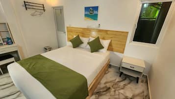 A hotel room with a bed, a nightstand, a desk, and a window.