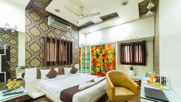 A hotel room with a bed, a desk with a laptop, a chair, a mirror, and a ceiling fan.