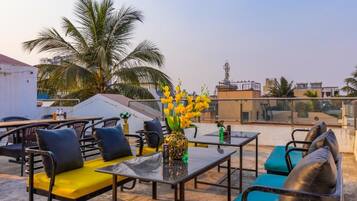 A rooftop terrace with outdoor seating, a decorative vase, and a view of the cityscape.