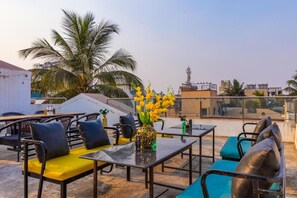 Una terraza en la azotea con mobiliario exterior, un jarrón decorativo y vistas a la ciudad.