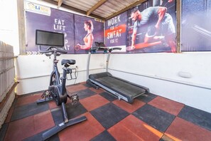 Un gimnasio con equipo de ejercicio, caminadora y carteles motivacionales en la pared.