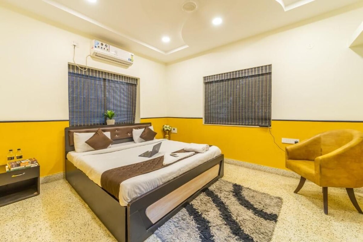 A hotel room with a bed, a nightstand, a chair, and a window with blinds.