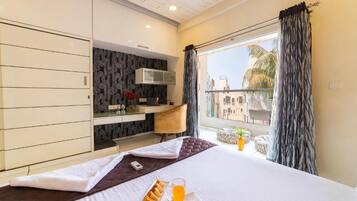 A hotel room with a bed, a desk, and a window with curtains.