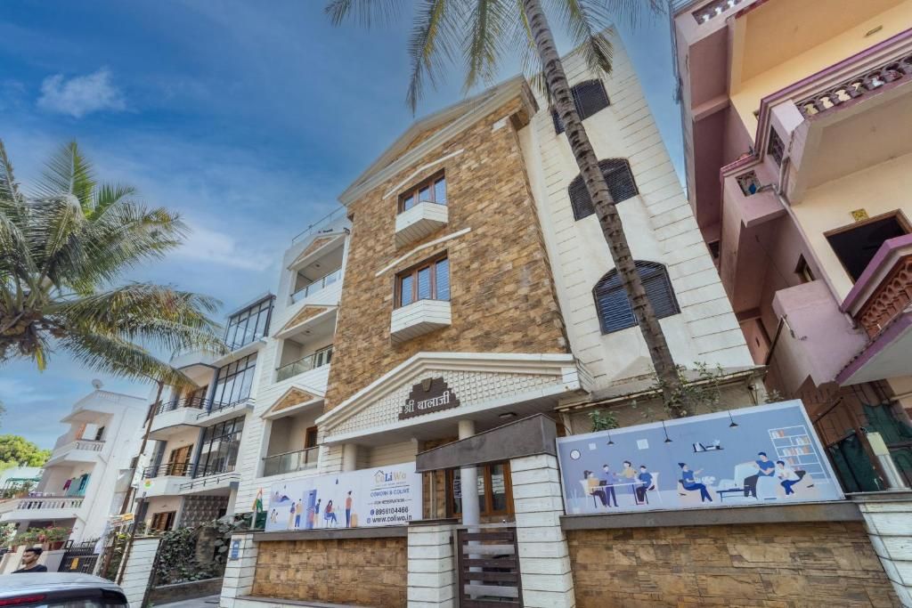 A multi-story residential building with balconies, a stone facade, and a signboard.