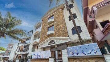 A multi-story residential building with balconies, a stone facade, and a signboard.