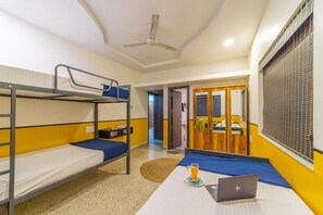 Un dormitorio con literas, un escritorio con una computadora portátil y una ventana con persianas.