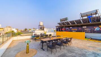 A rooftop terrace with outdoor seating, a water tank, and a large advertisement.