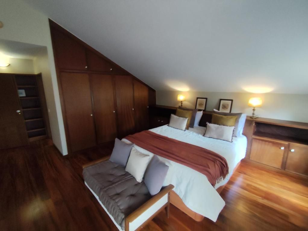 A bedroom with a large bed, a wooden bench, and a staircase leading to a loft area.