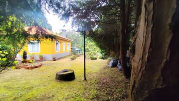 A yellow house with a red roof, surrounded by a grassy yard and trees.