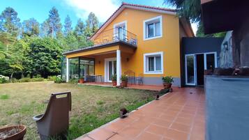 Una casa de dos pisos con fachada amarilla, un balcón y un patio cubierto.