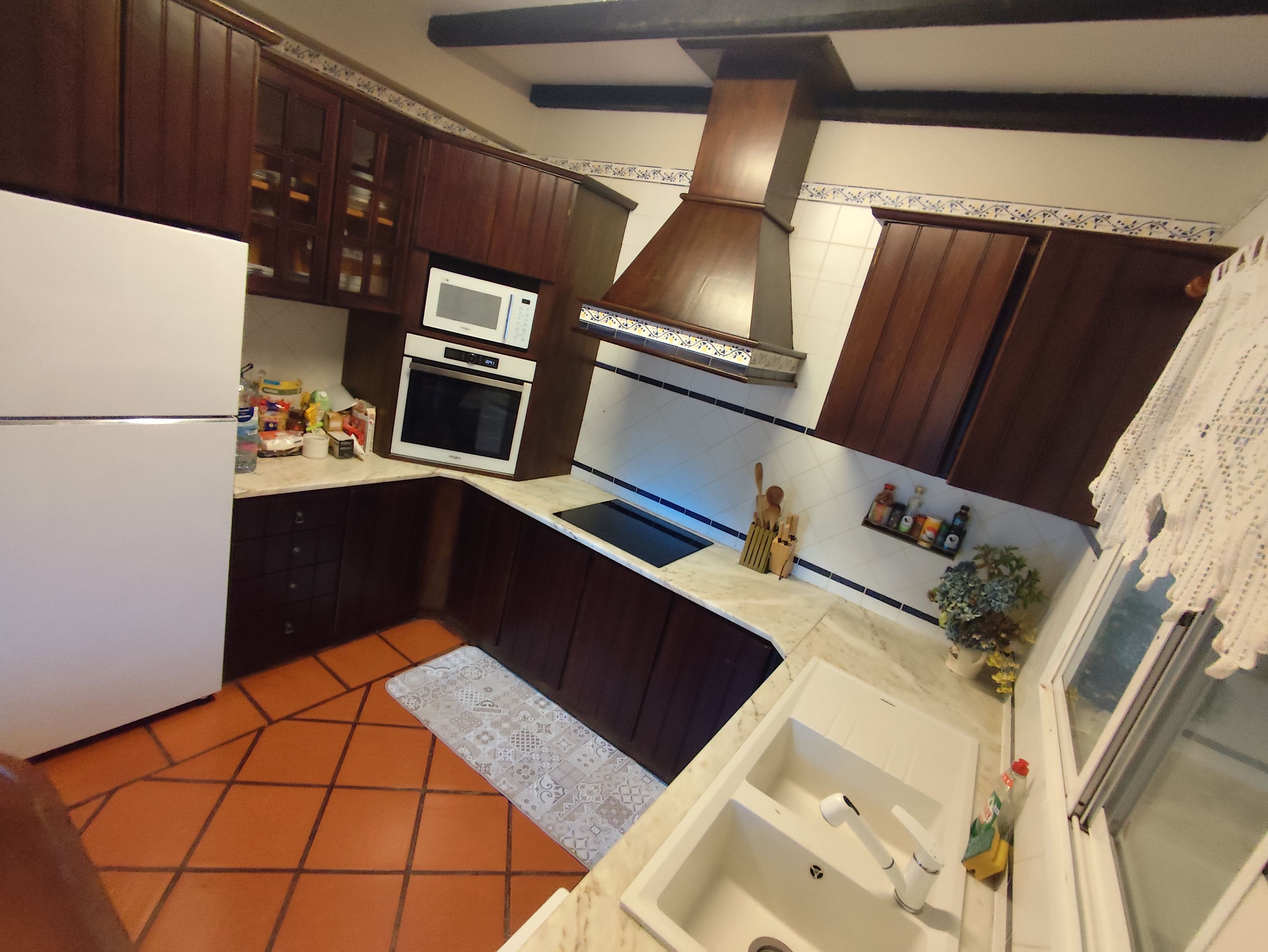 Una cocina compacta equipada con refrigerador, microondas, horno y lavamanos con ventana arriba.