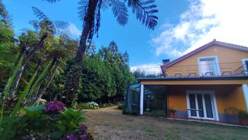 En bostadsfastighet med ett glashus/vinterträdgård, en inhägnad trädgård och ett hus med balkong.