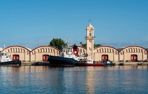 A harbor with a large ship docked, a tower, and several numbered buildings. - 3 minutes from the beach—everything is within walking distance (Grau i Platja)