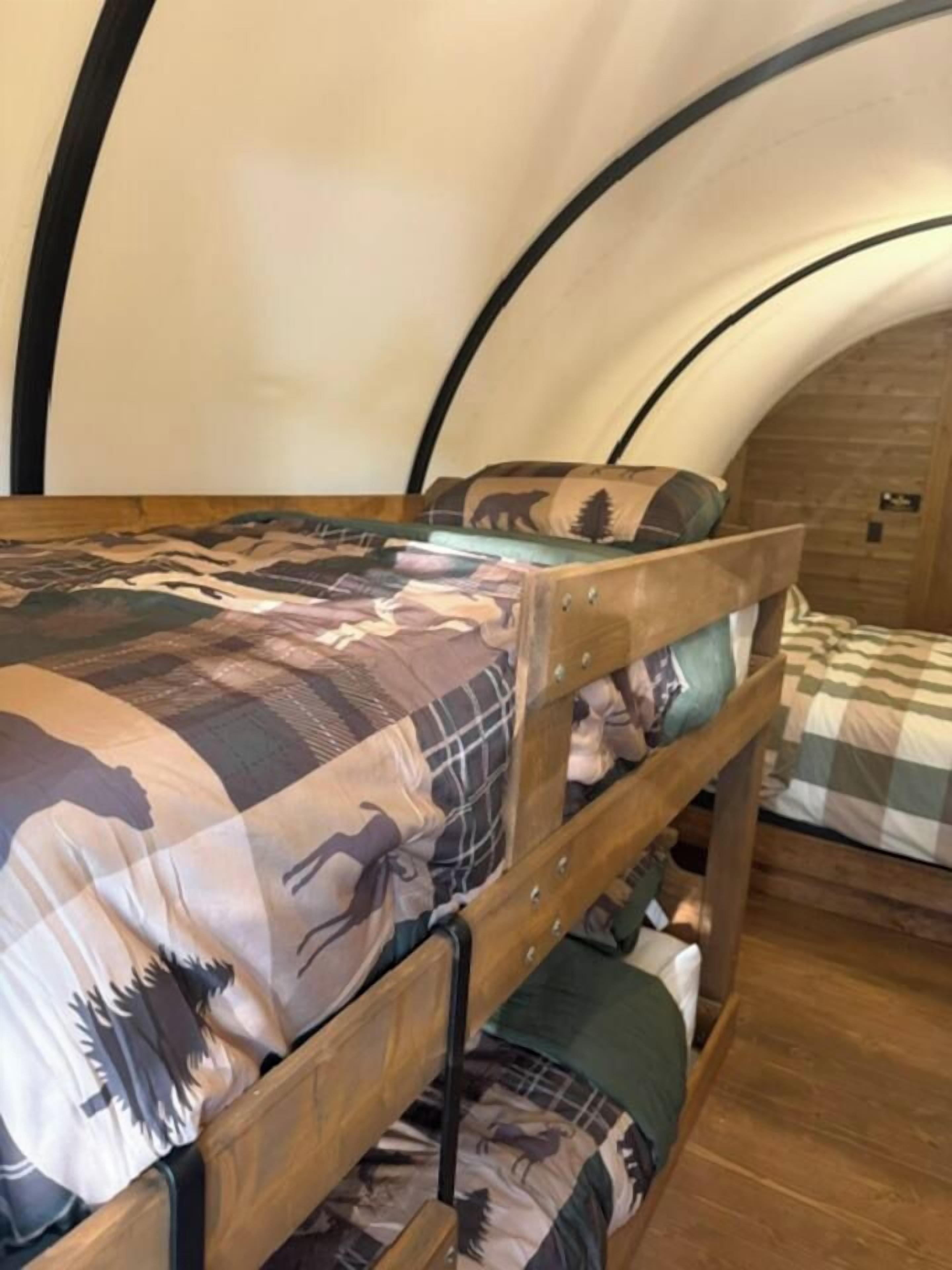 A bunk bed with a patterned bedspread and a wooden headboard.