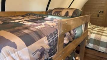 A bunk bed with a patterned bedspread and a wooden headboard.