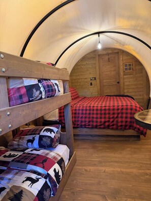 Een stapelbed met een rood-zwarte geruite dekbedovertrek en een houten hoofdbord.