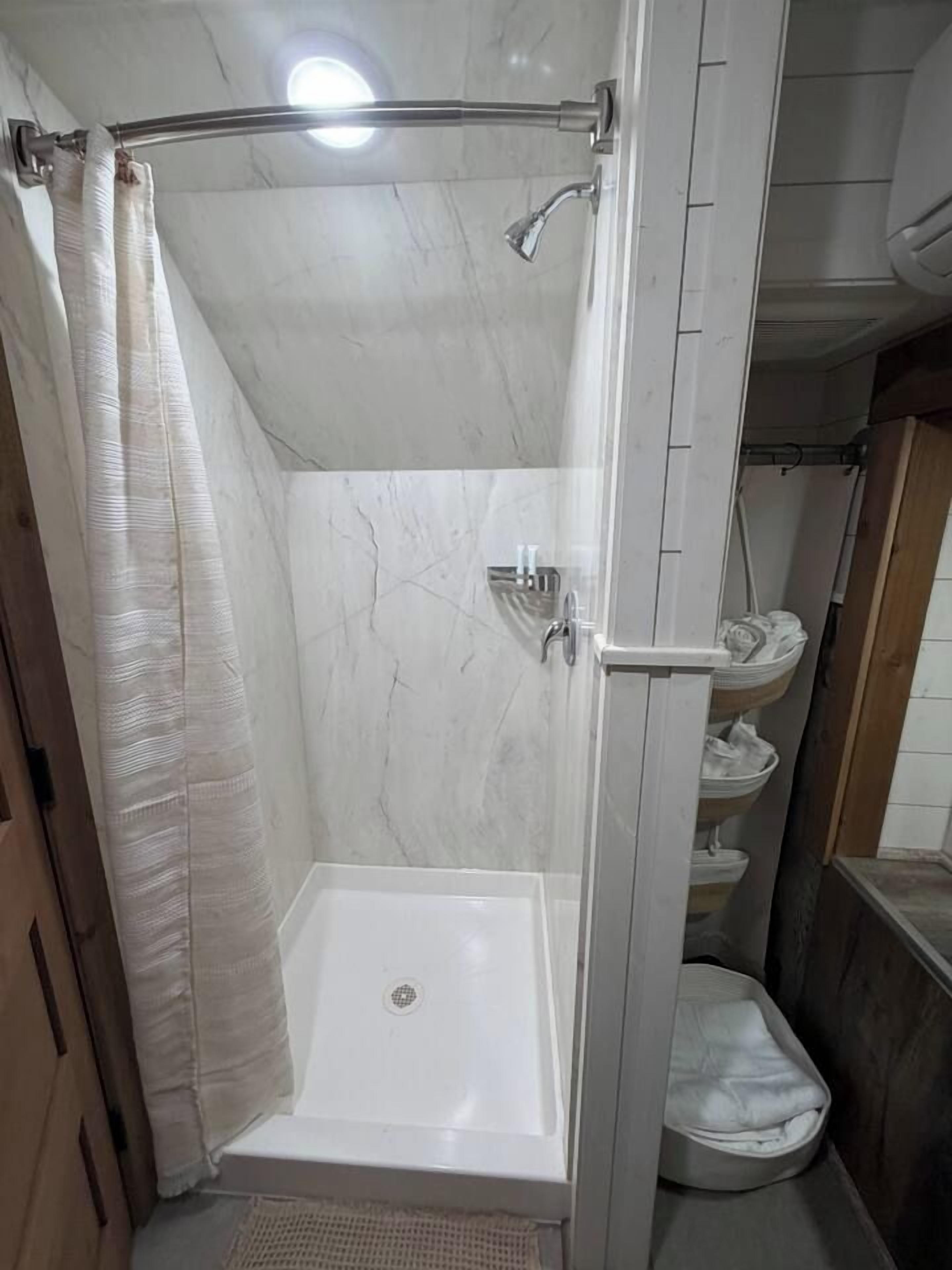A walk-in shower with a glass door, a showerhead, and a white tiled wall.