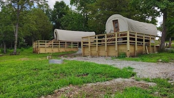 A covered wagon with a wooden structure and a dirt path leading to it.