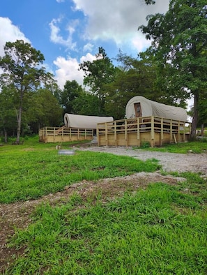 A covered wagon with a wooden structure and a dirt path leading to it.