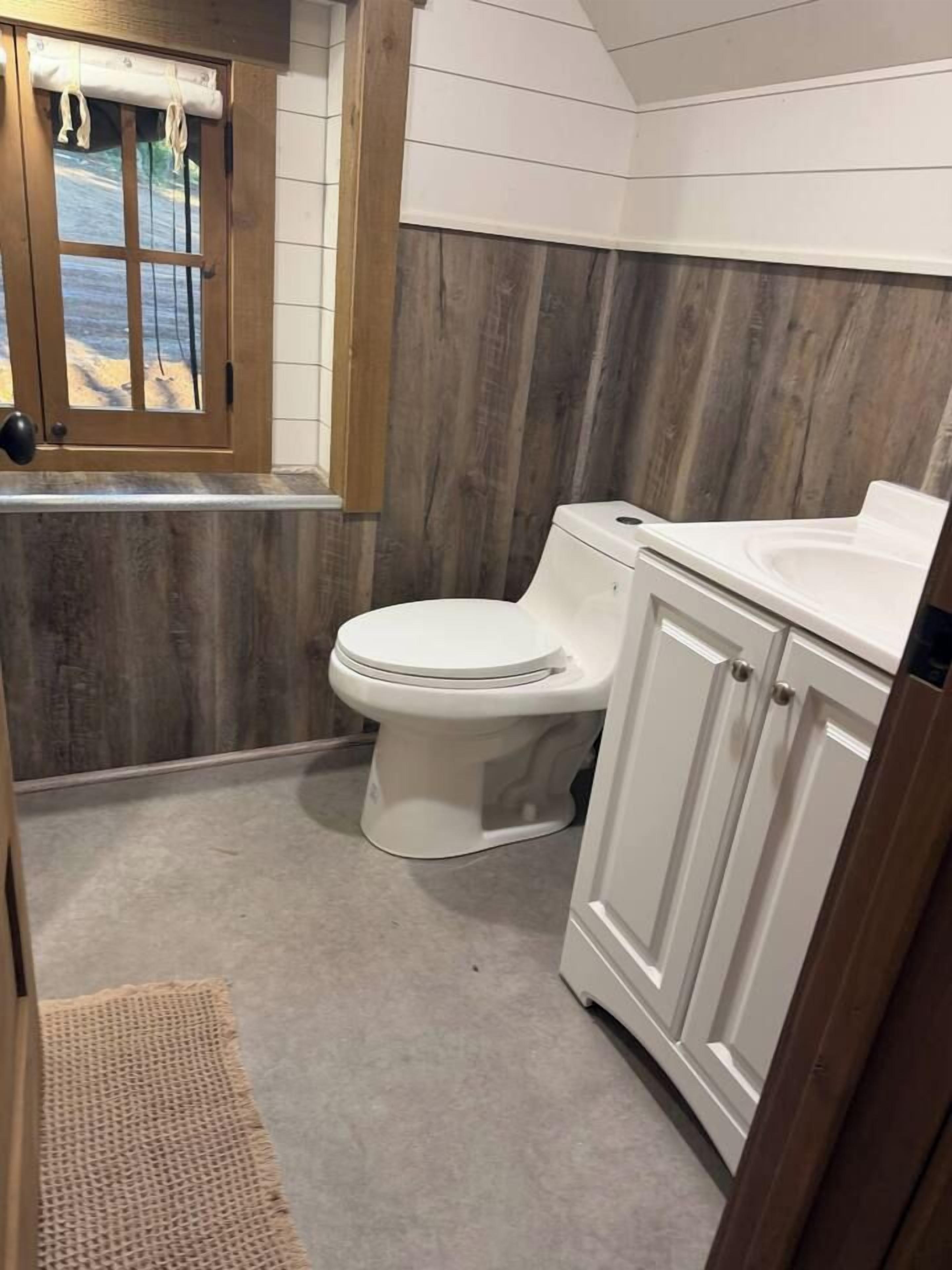 A bathroom with a wooden wall, a white toilet, and a white sink.