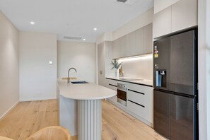 A modern kitchen with a built-in island, a stainless steel refrigerator, and a microwave. - Spacious 3-bed Townhouse In Mile End (Adelaide)