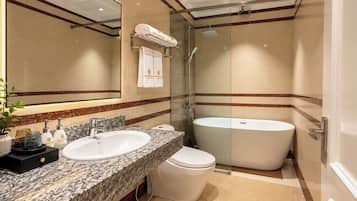 A modern bathroom with a large mirror, two sinks, a toilet, and a freestanding bathtub.