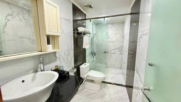 A bathroom with a large sink, toilet, and glass-enclosed shower.